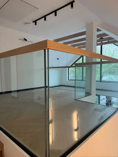 Szklana balustrada z drewnianą poręczą wokół otworu schodów w salonie