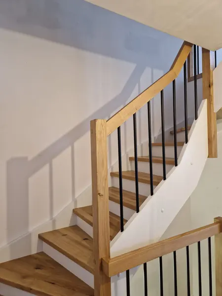Dębowe schody na beton z balustradą z czarnych tralek